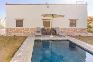 una piscina con sedie e ombrellone accanto a una casa di Amazing Home in Agafay With Pool & garden a Marrakech