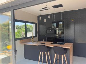 a kitchen with a counter and two stools at a bar at Villa luxueuse Piscine Chauffée & SPA in Villetelle