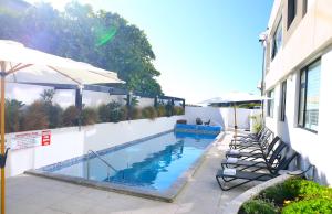 ein Swimmingpool mit Stühlen und Sonnenschirmen neben einem Gebäude in der Unterkunft Belle Mer Beachfront Apartments - Self Serviced in Mount Maunganui + 115 Fotos