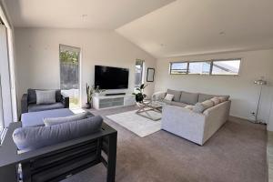 a living room with two couches and a tv at Easy Beach Holiday in Mount Maunganui