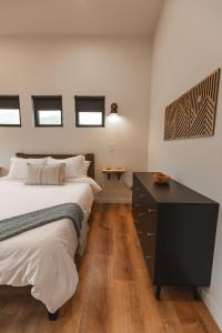 Schlafzimmer mit einem Bett, einer Kommode und Fenstern in der Unterkunft Hiker's Haven at Three Suns Cabins in Slade