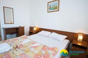 two beds in a hotel room with two lamps at Apartments Becici in Budva