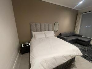 a bedroom with a large white bed and a chair at The Capital Trilogy Menlyn Maine Apartment in Pretoria