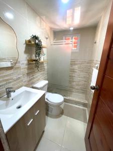 a bathroom with a white toilet and a sink at Alojamiento San Isidro in La Grúa