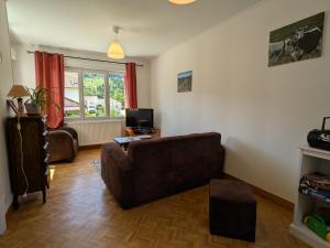 a living room with a couch and a television at Gîte confortable avec terrasse et vue montagne, proche loisirs et pistes - FR-1-589-755 in Saulxures-sur-Moselotte