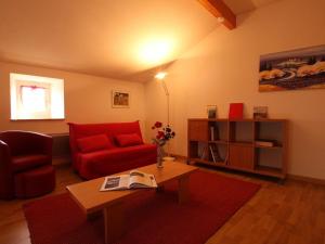 a living room with a red couch and a table at Maison pittoresque avec terrasse et BBQ, calme près de Langeac - FR-1-582-124 in Langeac