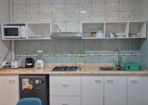 a kitchen with white cabinets and a black refrigerator at Hostal Iria in Antofagasta