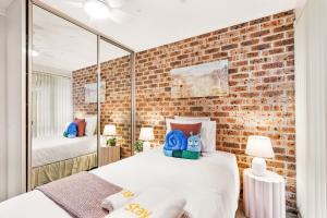 a bedroom with two beds and a brick wall at StayAU Cozy 3BR Suburban Retreat in Ingleburn in Ingleburn