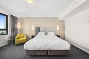 a bedroom with a large bed and a yellow chair at Bright Studio with Pool Access in Parramatta in Sydney