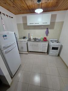 a kitchen with white appliances and a wooden ceiling at Departamentos Los Abuelos in General Acha