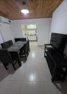 a dining room with a table and chairs and a television at Departamentos Los Abuelos in General Acha