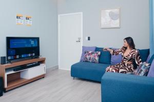 a woman sitting on a couch playing a video game at Santa Rita apartament#4 near restaurants in Danlí