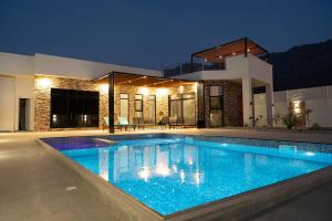 a swimming pool in front of a house at night at Sifah Breeze in Dhīqdah