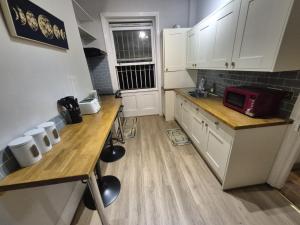 a small kitchen with white cabinets and a red microwave at Spacious Apartment in London in London +15 photos