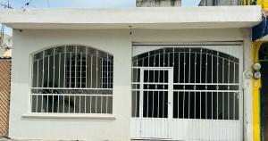 a white garage with two windows and a door at Casa Michel in Tepic