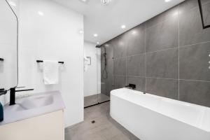a white bathroom with a tub and a sink at Unit 4 Tuscany Shores in Marcoola +32 photos