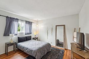 a bedroom with a bed and a television and a mirror at Parking,Pet,2bd,2b,WIFI,Smart TVs,Walk to Food,Fun in Long Beach