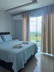 um quarto com uma cama e uma janela grande em Apartamento Praia do Forte, Cabo Frio, Frente mar em Cabo Frio