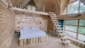 SānglaShepherd's Lore Camps & Resort的树屋里的一间卧室，有一张床和一个楼梯