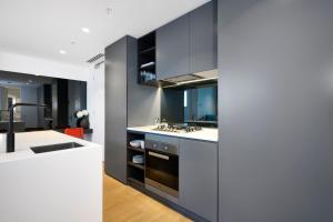 a kitchen with black cabinets and a sink at Stay Fit & Relax - 2BR with Gym & Spa in Melbourne