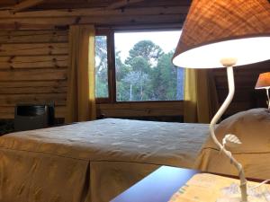 ein Schlafzimmer mit einem Bett und einer Lampe auf einem Tisch in der Unterkunft Apart al Lago in Villa Pehuenia