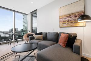 ein Wohnzimmer mit Sofa und Tisch in der Unterkunft West Side Spencer St Apt w Marvel Stadium View in Melbourne