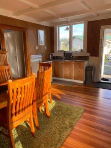 a kitchen with three wooden chairs and a sink at Waitomo Farmstay Cottage 1 - Kauri Cottage in Waitomo Caves