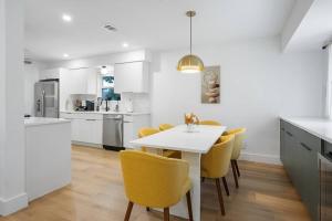 a kitchen and dining room with a white table and yellow chairs at Stylish Austin Escape 4BR, 2BA, Minutes from Domain, Q2 Stadium in Austin
