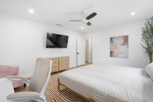 a white bedroom with a bed and a chair at Stylish Austin Escape 4BR, 2BA, Minutes from Domain, Q2 Stadium in Austin