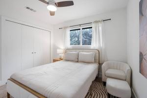 a white bedroom with a bed and a chair at Stylish Austin Escape 4BR, 2BA, Minutes from Domain, Q2 Stadium in Austin