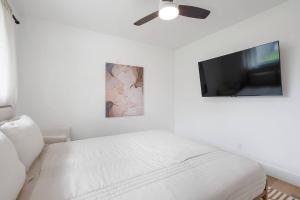 a white bedroom with a bed and a flat screen tv at Stylish Austin Escape 4BR, 2BA, Minutes from Domain, Q2 Stadium in Austin