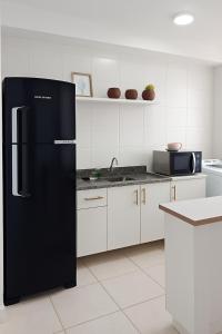 frigorifero nero in cucina con armadi bianchi di Apartamento Ponta Negra Manaus - Próximo ao Aeroporto a Manaus
