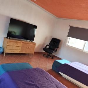 a bedroom with a tv and a chair and a desk at Casa Colibrí Ahuatepec Cuernavaca in Cuernavaca