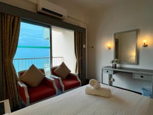a hotel room with a bed and chairs and a large window at Maisie Rainbow Penang in Tanjung Bungah +55 photos