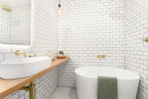 a white bathroom with a tub and a sink at 3 Bedroom Split level terrace at Bondi Junction in Sydney