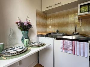 una cucina con piatti e un vaso di fiori su un bancone di Studio Charmant au Coeur d'Excideuil - Animaux Bienvenus - FR-1-839-6 a Excideuil Altre 8 foto