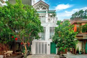 a white house with a green door and trees at Aries's House, Villa 4BR Near the Sea, Right in the Center in Da Nang