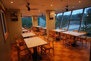 a restaurant with tables and chairs and large windows at Hotel river view sringeri in Sringeri