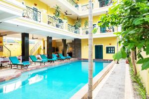 a pool in a hotel with blue chairs and trees at Golden Banana Residence in Siem Reap