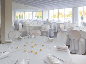 une salle remplie de tables et de chaises blanches avec des verres et des serviettes. dans l'établissement Pietrabianca Exclusive Resort, à Pomigliano dʼArco