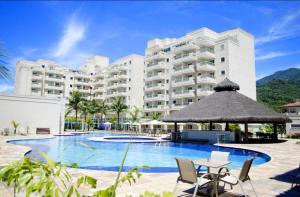 a large hotel with a large swimming pool and chairs at Flat Porto Marina Mont Blanc in Mangaratiba