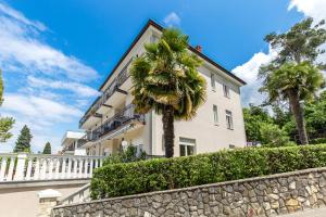 a building with a palm tree in front of it at Apartments & Rooms Milcetic M in Malinska