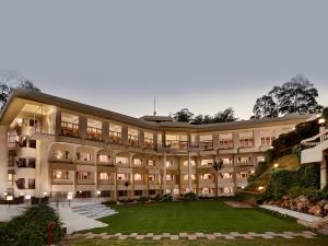 a large building with a lawn in front of it at Sinclairs Retreat Ooty in Ooty