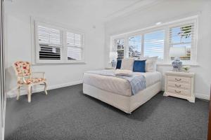 a bedroom with a bed and a chair and windows at Santa Maria - Saltwater Pool, Exquisite Style in Wagga Wagga
