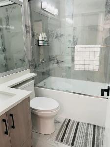 a bathroom with a toilet and a tub and a sink at New and Modern 1 bedroom suite near beach in Surrey
