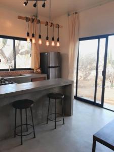 a kitchen with two bar stools and a counter with windows at Zen Studio Full Kitchen & Outdoor Chill Space in La Ventana