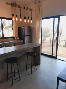 a kitchen with two bar stools and a counter with windows at Zen Studio Full Kitchen & Outdoor Chill Space in La Ventana +13 photos