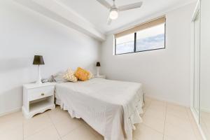 una camera da letto bianca con un letto e una finestra di Panoramic Ocean View CBD Appartment a Yeppoon