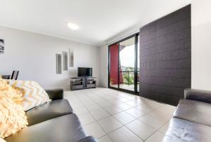 un soggiorno con un divano e una televisione di Panoramic Ocean View CBD Appartment a Yeppoon