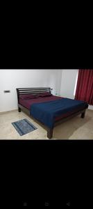 ein Schlafzimmer mit einem Bett mit blauer Bettdecke und einem Fenster in der Unterkunft Holiday cottage in Madikeri